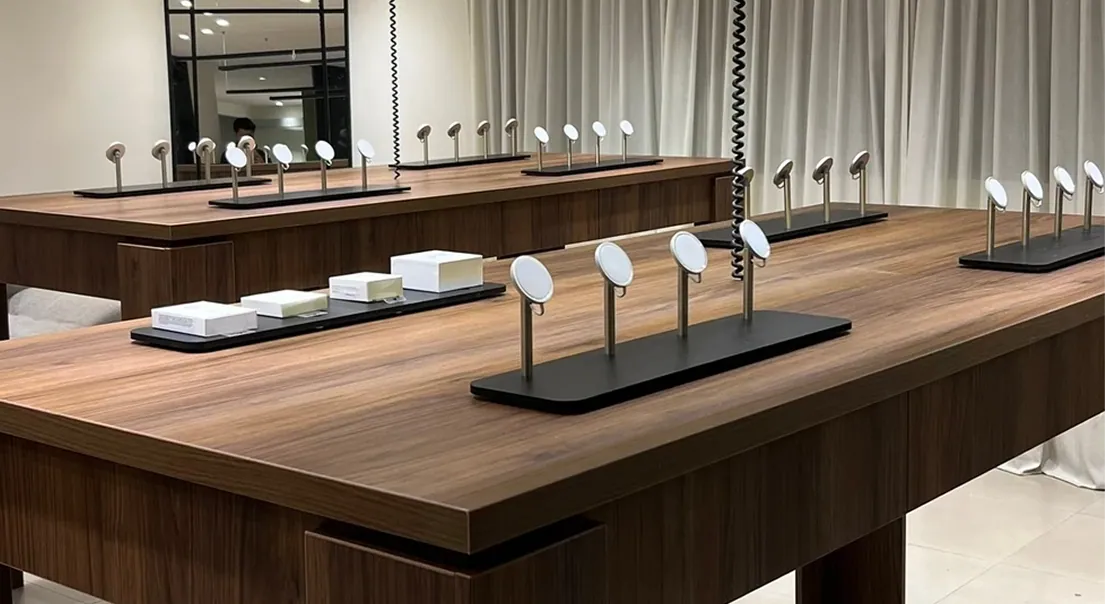 Mesas de exhibición en madera oscura para un local comercial, con luminarias lineales
