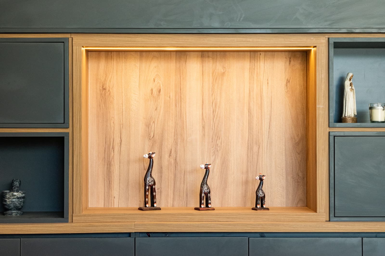 Detalle de un nicho iluminado: canto de madera y frente texturado