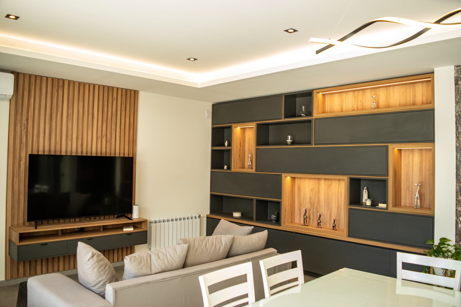 Living completo realizado por Nordica: panel de listones de madera, mueble de TV flotante y biblioteca con nichos iluminados