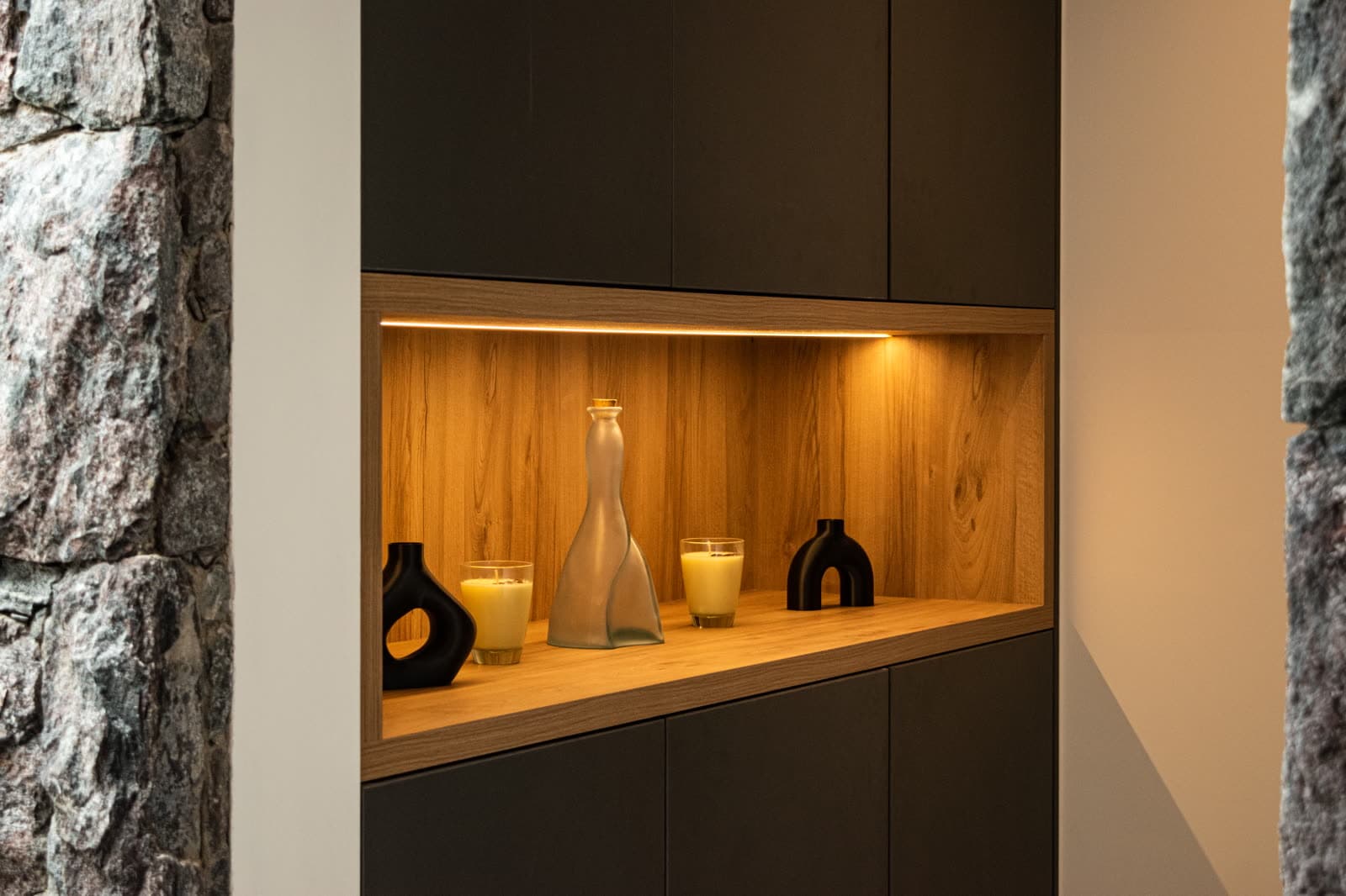 Nicho iluminado de madera junto a una pared de piedra